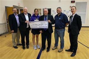 Kelli Wittman holding a novelty check & SHEF Board smiling for the Teacher Excellence Grant presentation at WCES